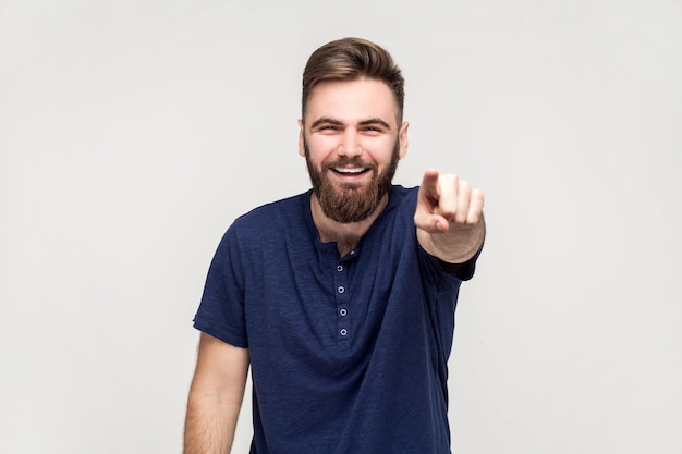 Homem bonito divertido rindo alto apontando o dedo para a câmera indicando idiota ridículo