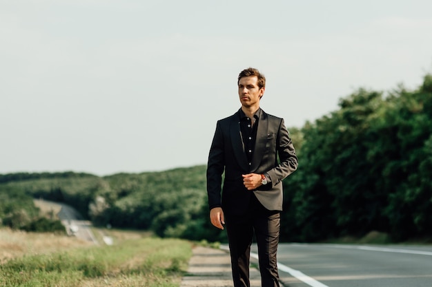 Homem bonito e elegante caucasiano em poses de terno preto perto da rua