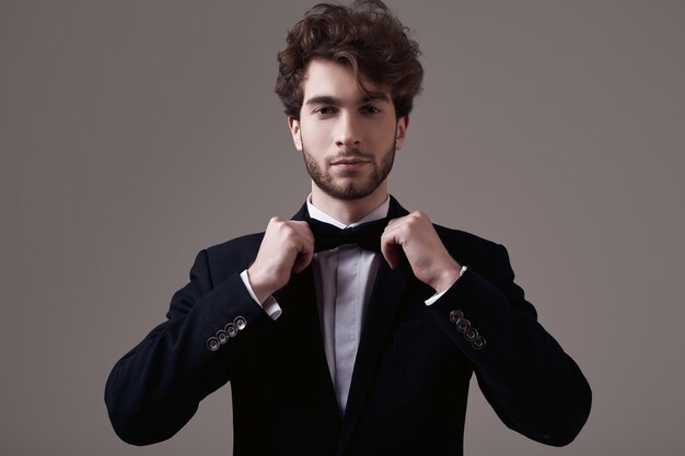 Homem bonito e elegante com cabelos ondulados vestindo esmoquinho.