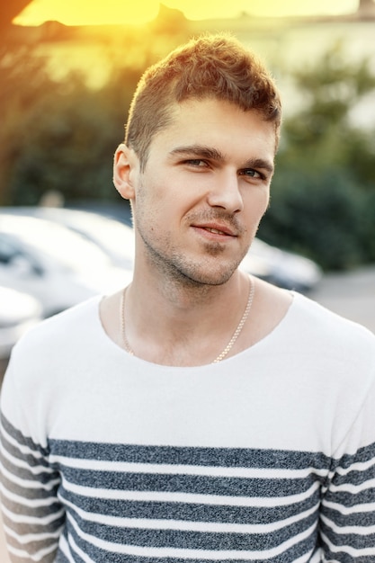 Homem bonito e elegante, com uma barba, uma camisola ao pôr do sol.