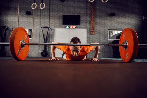 Homem bonito e em forma faz treino de braço e peito no centro de treinamento