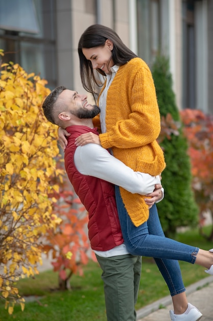 Homem bonito e encantado sorrindo para a namorada enquanto é feliz junto com ela