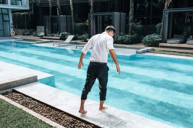 Homem bonito e esguio em traje de negócios se preparando para pular na água da piscina