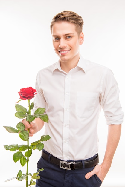 Homem bonito e feliz com uma rosa vermelha segurando a mão no bolso