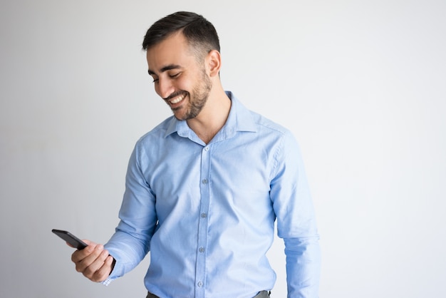 Homem bonito e feliz olhando a tela do smartphone