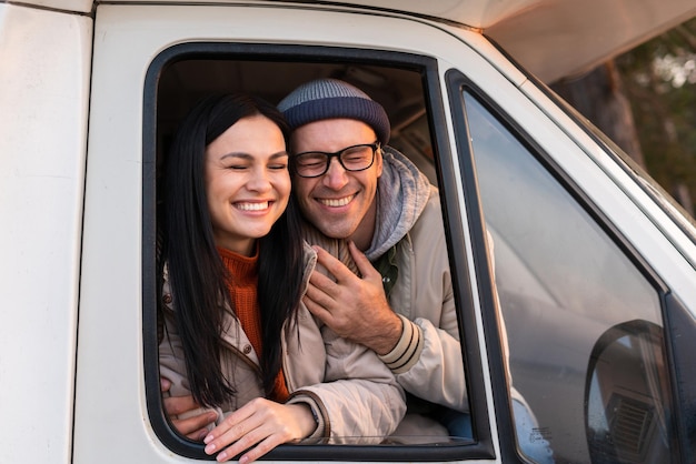 Homem bonito e mulher encantadora, abraçando e olhando do carro com inspiração. Conceito de acampamento. Foto