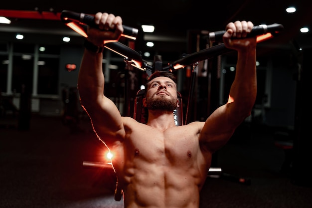 Foto homem bonito e poderoso fazendo supino fisiculturista em forma trabalhando duro na academia pessoa esportiva treinando sem roupas esportivas