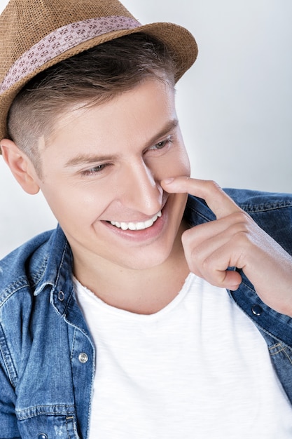 Homem bonito e sorridente em jeans e chapéu