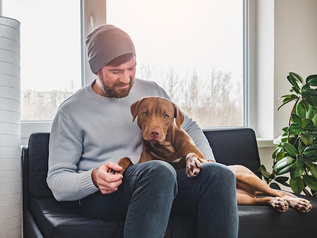 Homem bonito e um filhote de cachorro encantador. Fechar-se