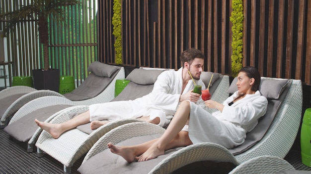 Homem bonito e uma mulher bonita estão relaxando no spa, bebendo coquetéis não alcoólicos