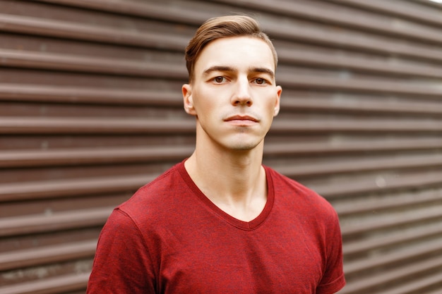 Homem bonito elegante com penteado em uma camisa vermelha em um metal