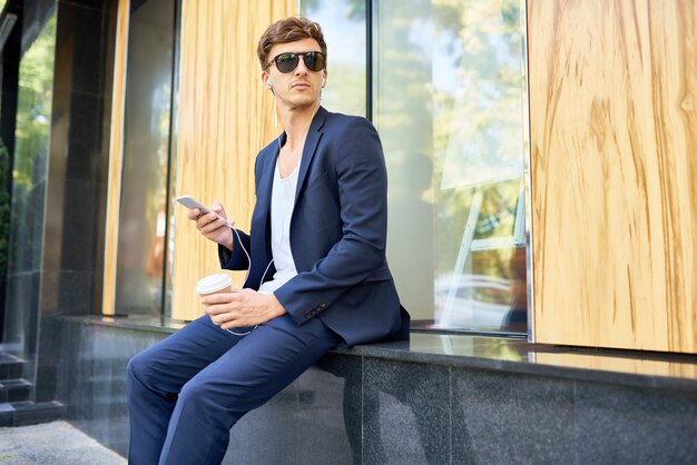 Homem bonito elegante, segurando o Smartphone