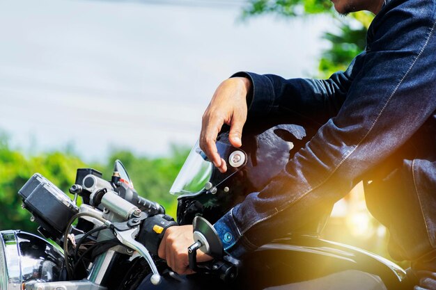 Homem bonito em jean está sentado na moto vintage e colocar um capacete nele