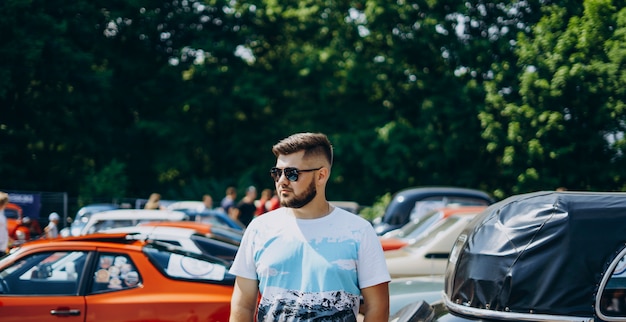 Foto homem bonito em óculos de sol perto de carros retrô.