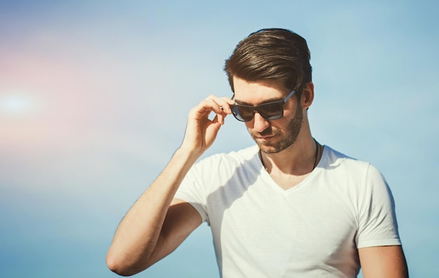 homem bonito em óculos de sol sobre céu azul. Beleza masculina, moda. cara da moda