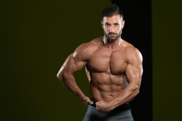 Homem bonito em pé forte na academia e flexionando os músculos Muscular Atlético Fisiculturista Modelo de fitness posando após exercícios