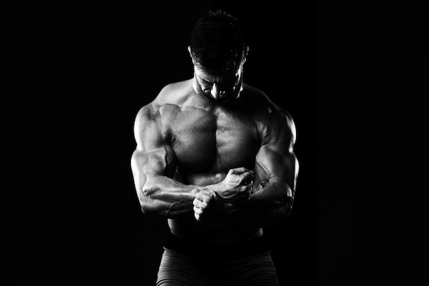 Homem bonito em pé forte na academia e flexionando os músculos Muscular Atlético Fisiculturista Modelo de fitness posando após exercícios