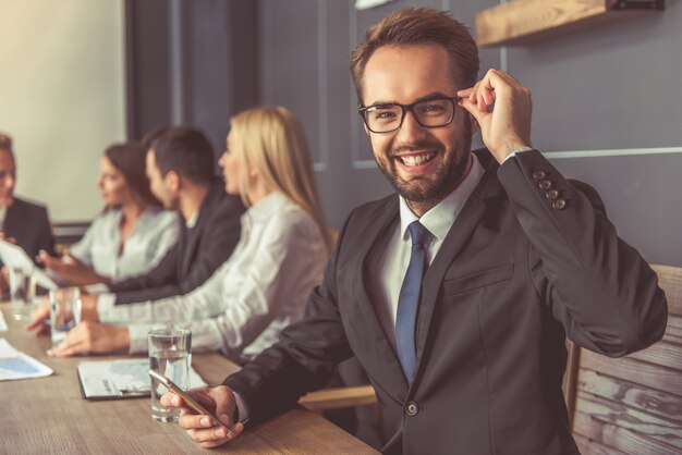 Homem bonito em primeiro plano está usando um smartphone