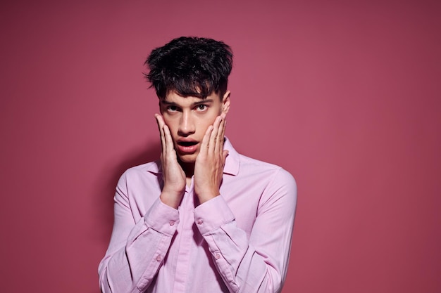 Homem bonito em uma camisa rosa gesticulando com as mãos fundo rosa inalterado