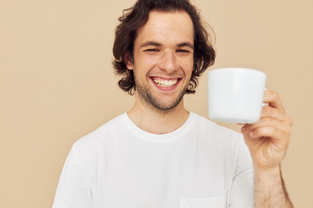 Homem bonito em uma camiseta branca com uma caneca em fundo isolado na mão