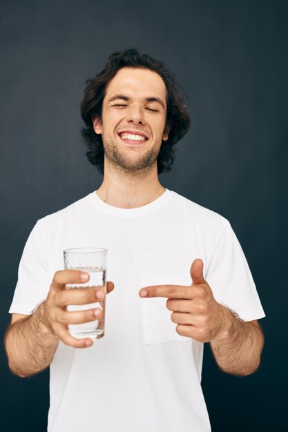 Homem bonito em uma camiseta branca copo de água estilo de vida inalterado