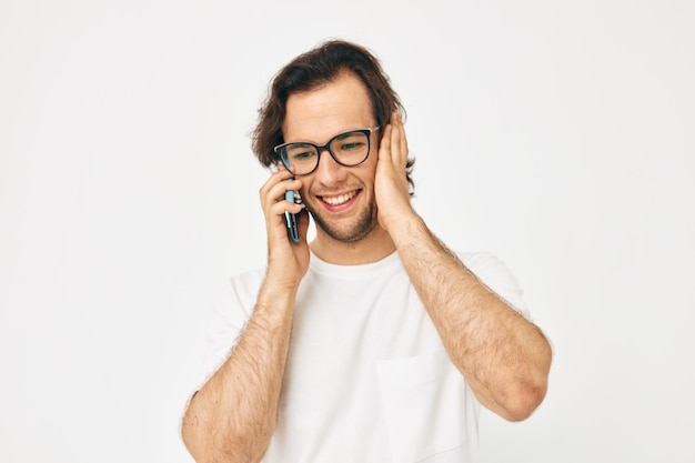 Homem bonito em uma comunicação de camiseta branca por telefone isolado de fundo