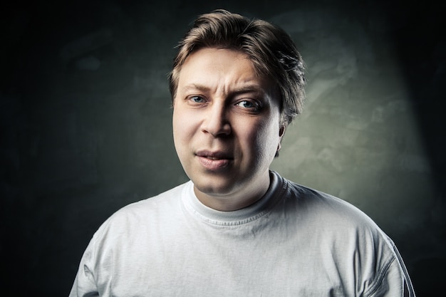 Foto homem bonito emocional de meia-idade duvidando de um fundo cinza escuro