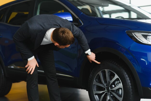 Homem bonito escolhendo um carro em um show room