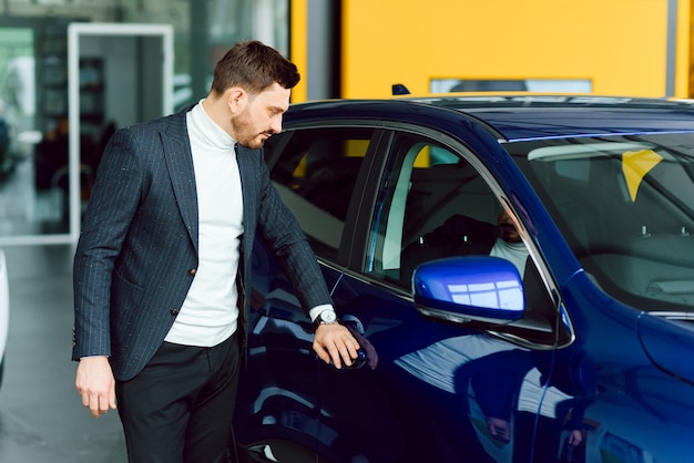 Homem bonito escolhendo um carro em um show room