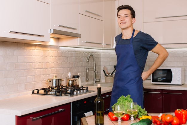 Homem bonito está cozinhando na cozinha e sorrindo