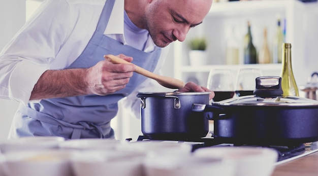 Homem bonito está cozinhando na cozinha e sorrindo