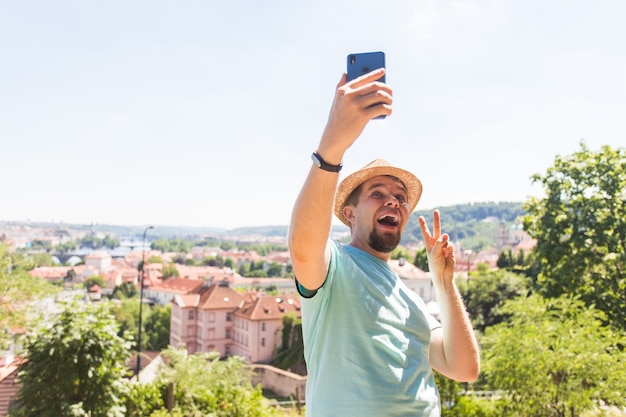 Homem bonito está tirando uma selfie ao ar livre. Pessoas caucasiano, natureza, estilo de vida, pessoas, tecnologia