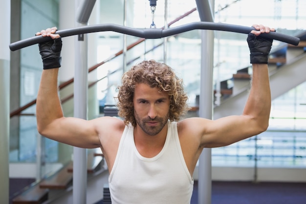 Homem bonito exercitando em uma máquina lat na academia