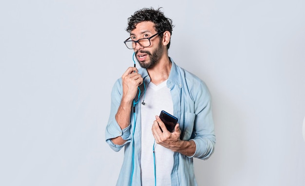 Foto homem bonito falando com fone de ouvido segurando celular jovem de óculos com fones de ouvido isolados