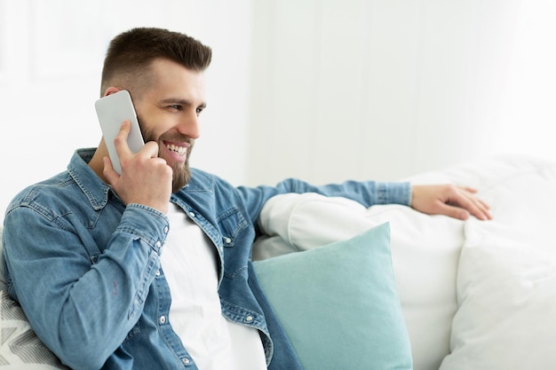 Homem bonito falando no telefone relaxando no sofá