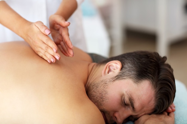 homem bonito fazendo massagem em salão de spa