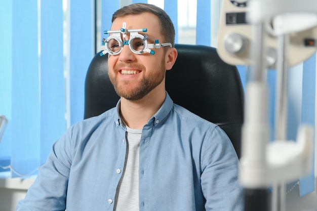 Homem bonito, fazendo um exame oftalmológico na clínica oftalmológica, verificando a retina de um olho masculino fechado