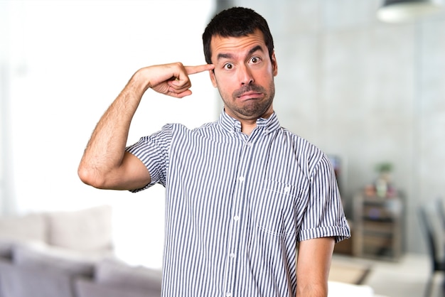 Homem bonito fazendo um gesto louco dentro da casa