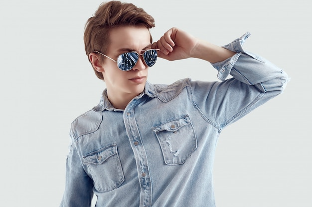 Homem bonito hipster em óculos de sol da moda vestindo jaqueta jeans