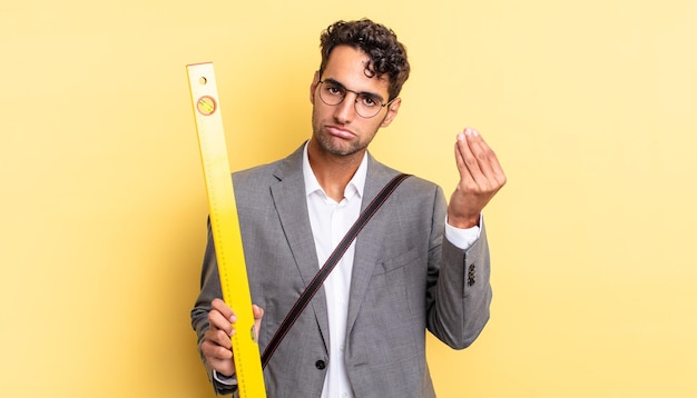 Homem bonito hispânico fazendo gesto de capice ou dinheiro dizendo para você pagar o conceito de arquiteto