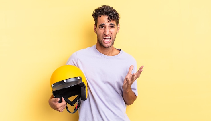 Foto homem bonito hispânico parecendo desesperado, frustrado e estressado. conceito de capacete de motocicleta