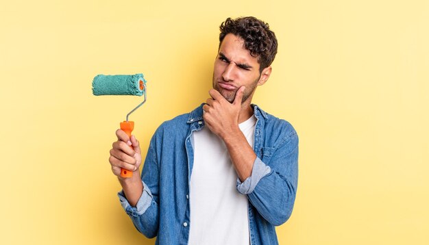 Homem bonito hispânico pensando, sentindo-se duvidoso e confuso. conceito de pintura a rolo