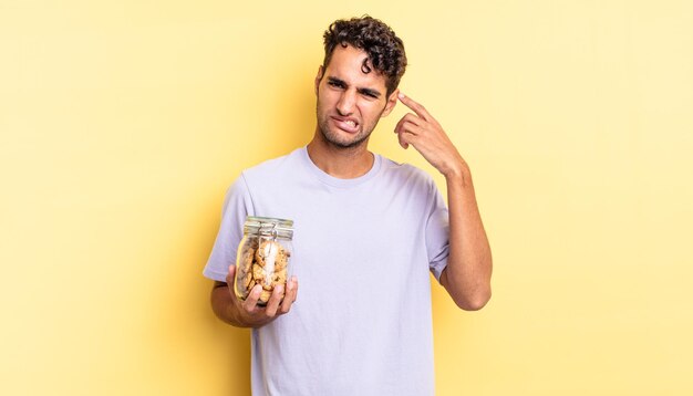 Homem bonito hispânico se sentindo confuso e perplexo, mostrando que você é louco. conceito de biscoitos