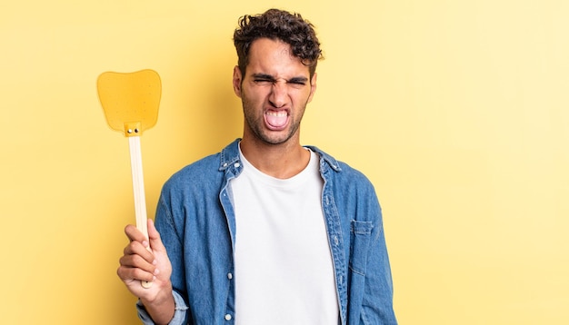 homem bonito hispânico se sentindo enojado e irritado e língua de fora. mata moscas conceito