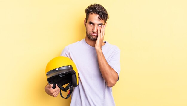 Homem bonito hispânico se sentindo entediado, frustrado e com sono depois de um cansativo. conceito de capacete de motocicleta