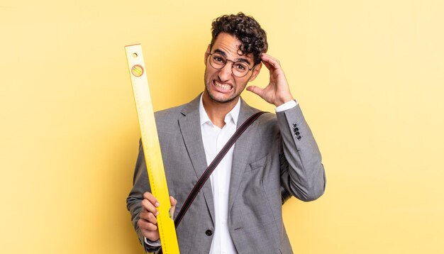 Homem bonito hispânico se sentindo estressado, ansioso ou com medo, com as mãos na cabeça. conceito de arquiteto