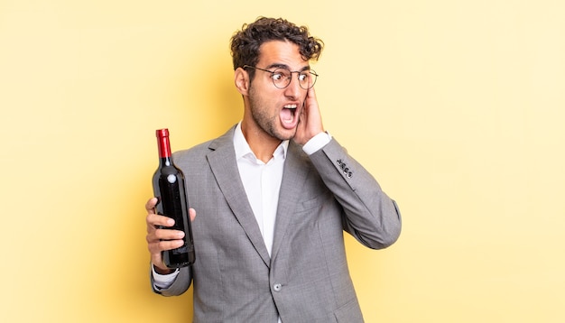 Homem bonito hispânico se sentindo feliz, animado e surpreso. conceito de garrafa de vinho