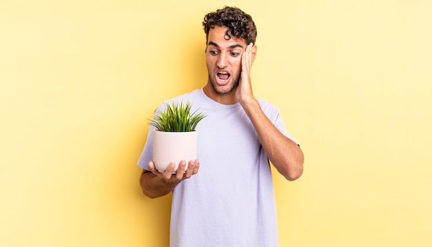 Homem bonito hispânico se sentindo feliz, animado e surpreso. conceito de planta decorativa