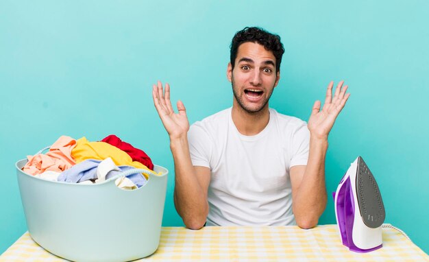 Homem bonito hispânico se sentindo feliz e surpreso com algo inacreditável conceito de ferro e roupas