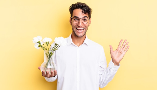 Homem bonito hispânico se sentindo feliz e surpreso com algo inacreditável. conceito de vaso de flores